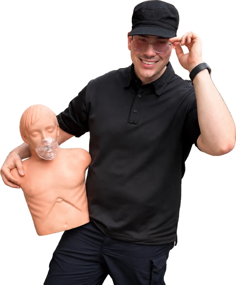 Thomas in his actual teaching photo, smiling and holding a CPR manikin